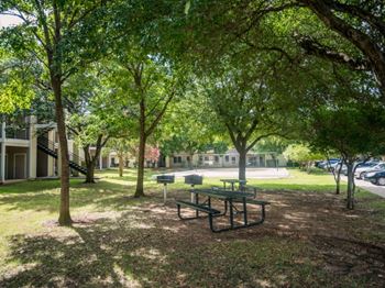 a picnic table in a park with trees and buildings in the background